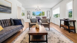 A spacious living room with a dark leather sofa, two armchairs, a wooden coffee table, and a large window with a view of greenery. - Entertainment Haven / Pool Table (Portland)