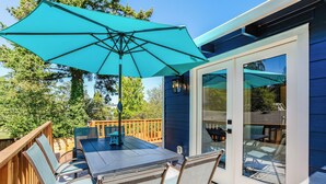 A patio with a table and chairs, a turquoise umbrella, and a glass door leading to a deck. - Entertainment Haven / Pool Table (Portland)