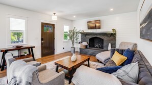 A living room with a fireplace, a sofa, a coffee table, and a door. - Entertainment Haven / Pool Table (Portland)