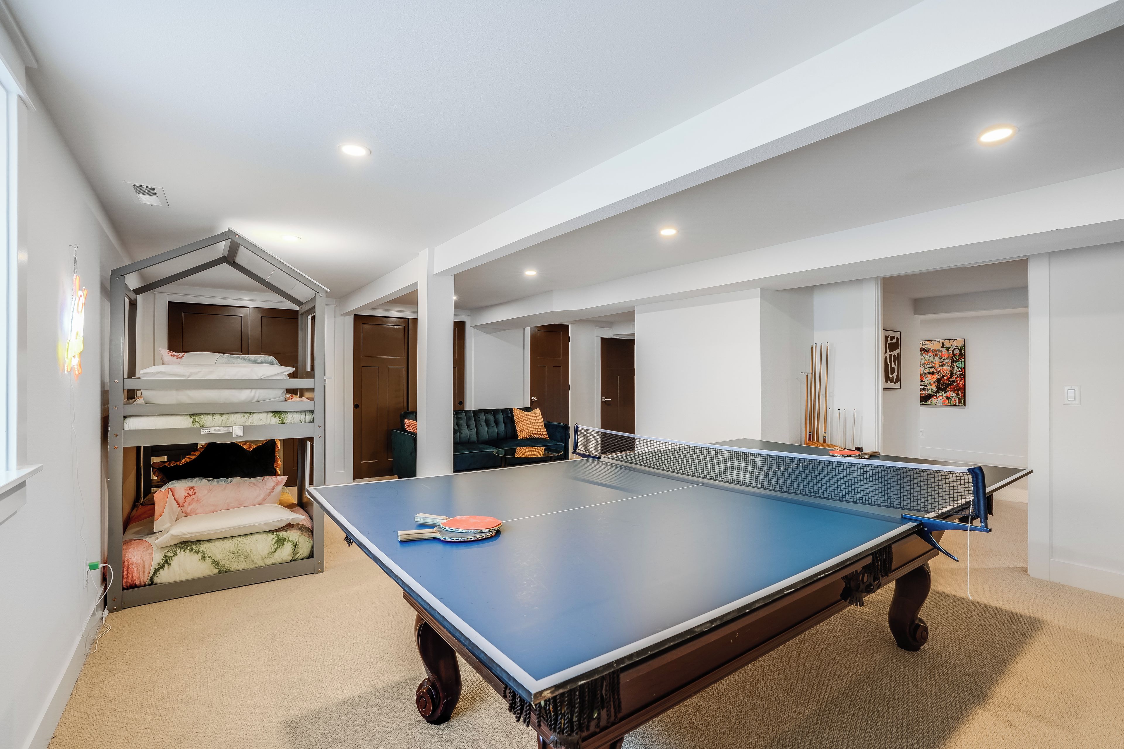 A spacious room with a ping pong table, a bunk bed, and a cozy seating area.