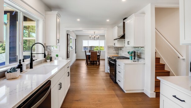 A modern kitchen with white cabinetry, a central island, and a dining area with a wooden table and chairs. - Entertainment Haven / Pool Table (Portland)