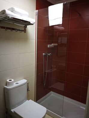 Une salle de bain avec une douche à parois de verre, des toilettes et un porte-serviettes avec des serviettes pliées.