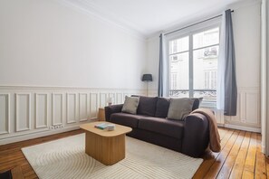 Een woonkamer met een donkerbruine bank, een houten salontafel en een wit tapijt.