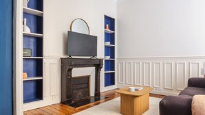 A living room with a fireplace, wooden flooring, a coffee table, and a sofa.