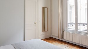 A room with a bed, a door, a window with a view, and a radiator.