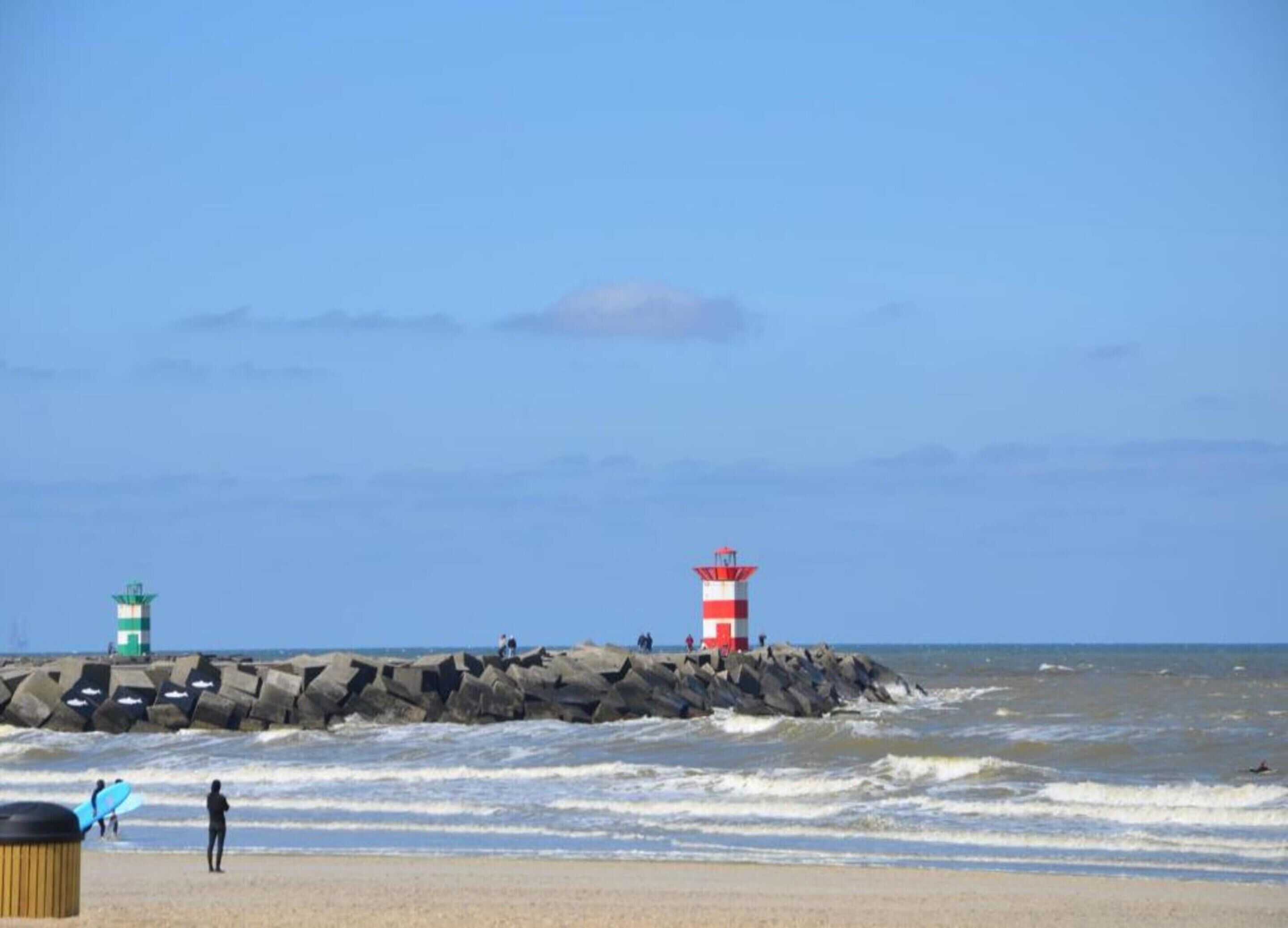 A beach with two lighthouses and a rocky breakwater.