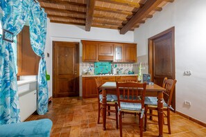 A kitchen with wooden cabinets, a dining table with chairs, and a tiled floor.