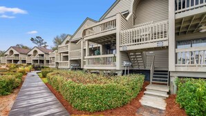 A row of wooden cabins with balconies, a wooden walkway, and a well-maintained garden area. - Beachfront w/ Breathtaking Views! 1BR/2BA, Pet Friendly, Amenity Access included (Seabrook Island)