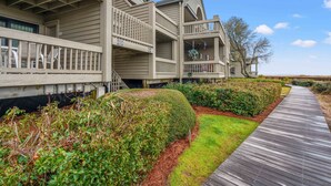 A multi-story building with balconies, a wooden deck, and well-maintained landscaping. - Beachfront w/ Breathtaking Views! 1BR/2BA, Pet Friendly, Amenity Access included (Seabrook Island)