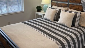 Una camera da letto con un letto, un comodino, una lampada e una finestra.