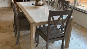 Zona pranzo con tavolo bianco, sei sedie e un vaso decorativo sul tavolo.