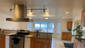 Una cucina moderna con piano cottura in acciaio inossidabile, mobili in legno e un'ampia finestra che permette l'ingresso di luce naturale.
