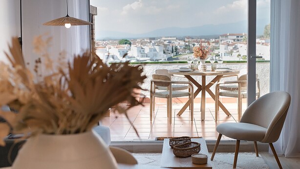 A dining area with a view of the city, a table set for two, and a chair. - WELCS APARTAMENTO 223 EMP con TERRAZA con VISTA (Empuriabrava)