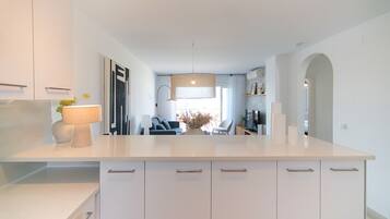 Een moderne keuken met witte kasten, een centraal eiland en een zithoek met een bank en stoelen.