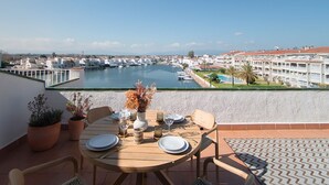 A dining area with a table set for four, overlooking a marina with boats and a pool. - WELCS APARTAMENTO 223 EMP con TERRAZA con VISTA (Empuriabrava)
