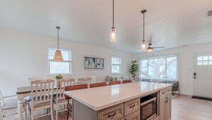 Una cocina amplia con una isla grande, armarios de madera e iluminación colgante.