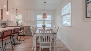 Una cocina moderna con armarios blancos, una mesa de comedor de madera y taburetes de bar.