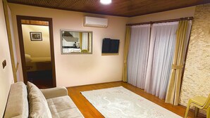 A living room with a sofa, a large rug, a flat-screen TV, and a window with curtains. - Ak Nature  (Trabzon)