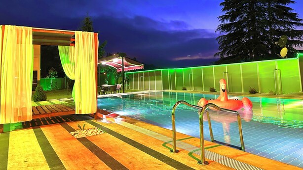 A swimming pool with a wooden deck and a covered seating area. - Ak Nature  (Trabzon)