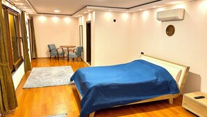 A bedroom with a bed, a bedside table, a chair, a small table, and an air conditioning unit. - Ak Nature  (Trabzon)