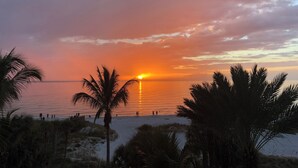 Une scène de plage avec des palmiers et un coucher de soleil sur l’eau.