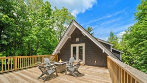 A cabin with a deck, Adirondack chairs, and a fire pit. - Elevation Escape - Beech Mtn home with game room, outdoor space (Beech Mountain)