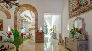 A spacious lobby with a polished floor, a brick archway, a large mirror, and a colorful tapestry.