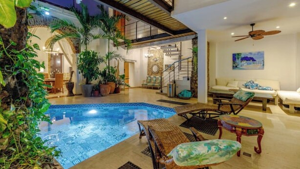 An indoor swimming pool with lounge chairs and a staircase leading to an upper level.