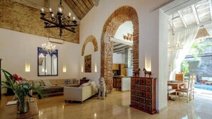 A spacious living area with a high ceiling, a fireplace, and a large arched brick structure.