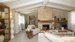 Un salón amplio con techo alto, chimenea, sofá, mesa de centro y estantería.