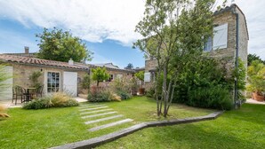 Una casa de piedra con tejado de tejas, un patio empedrado y un jardín bien cuidado con un sendero de madera.