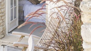 Una habitación con paredes de piedra, una cama, un cuadro y una puerta que da a otra habitación.