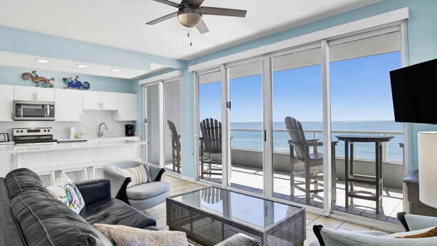 A modern living room with a large glass door leading to a balcony overlooking the ocean. - Silver Beach 506 | Pet Friendly, Direct Gulf Front, Great Location!! (Orange Beach)