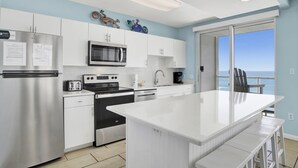 A modern kitchen with white cabinets, stainless steel appliances, and a large island. - Silver Beach 506 | Pet Friendly, Direct Gulf Front, Great Location!! (Orange Beach)