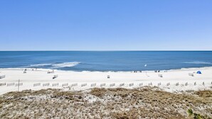 A beach with a clear sky, sandy shore, and a few people walking. - Silver Beach 506 | Pet Friendly, Direct Gulf Front, Great Location!! (Orange Beach)