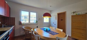 Une cuisine compacte avec un coin repas, une grande fenêtre et un luminaire suspendu rouge.