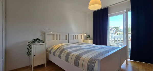 Une chambre à coucher avec un lit, une table de chevet et une plante en pot.