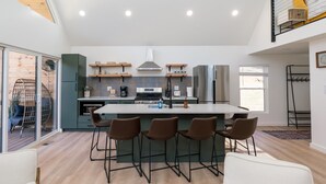 Een moderne keuken met een centraal eiland, barstoelen en een eethoek.