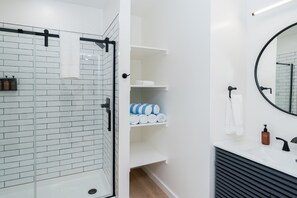 A modern bathroom with a glass shower enclosure, white tiled walls, a black sink, and a mirror. - Cabin Near Old Man's Cave · Sleeps 6 · Hot Tub (Laurelville)
