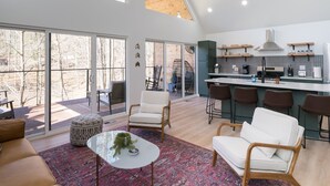 Een ruime woonkamer met hoge plafonds, grote ramen en een moderne keuken met een bar.