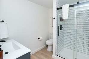 Une salle de bain moderne avec un lavabo blanc, des toilettes et une douche à parois de verre.