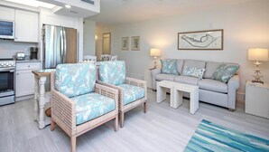 Una sala de estar moderna con un sofá, dos sillones, una mesa de centro y un comedor con mesa y sillas.