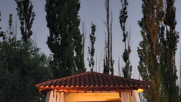 Un espace aménagé au bord de la piscine, comprenant un coin salon couvert, une table à manger et des chaises.