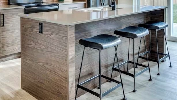 A modern kitchen with a central island, bar stools, a microwave, a refrigerator, and pendant lighting.