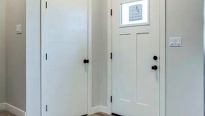 A hallway with two white doors, one with a small framed picture, and a carpeted area with wooden flooring.