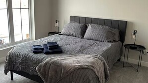 A bedroom with a large bed, two nightstands, and a window.