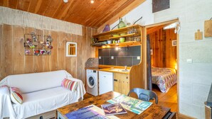 Een gezellige kamer met houten plafond, een bank, een kitchenette en een bed.