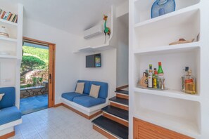 Un salon moderne avec un canapé bleu, un escalier et une bibliothèque contenant divers objets.