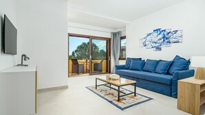 A modern living room with a sofa, a coffee table, a TV, and a balcony with a view.