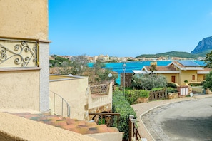 Zona residencial costera con vista despejada al mar, una calle pavimentada y un edificio con balcón.